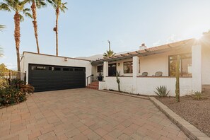 A modern house with a garage, a covered patio, and a well-maintained garden with palm trees and cacti. - Casa Coyote - A Ryson Property (Palm Springs)