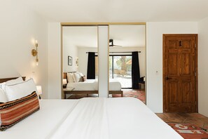 A hotel room with a bed, a wooden door, and a view of an outdoor seating area. - Casa Coyote - A Ryson Property (Palm Springs)