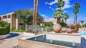 A hotel courtyard with a fountain, palm trees, and a swimming pool. - Convenient & Cozy Downtown - A Ryson Property (Palm Springs)