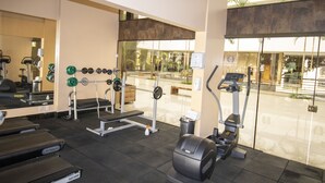 A gym with exercise equipment, a mirror, and a view of the outside. - Apart Hotel Le Jardin Caldas Novas (Caldas Novas)