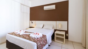 A hotel room with a bed, a nightstand, an air conditioning unit, and a lamp. - Apart Hotel Le Jardin Caldas Novas (Caldas Novas)