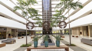 A spacious lobby with a central water feature, multiple seating areas, and indoor plants. - Apart Hotel Le Jardin Caldas Novas (Caldas Novas)
