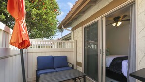 A patio with a blue sofa, a table, and a ceiling fan. - Simple Elegance - A Ryson Property (Indio)