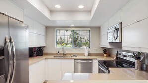 Een moderne keuken met roestvrijstalen apparatuur, een vaatwasser en een raam met zonwering.