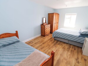 Une pièce avec deux lits en bois, une commode en bois et une fenêtre.