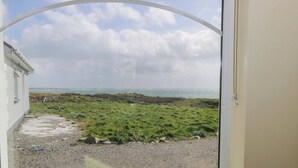 A view through a window with a framed picture of sailboats, a grassy area, and a building with a white exterior. - Tí Tom Nárta (Teeranea)