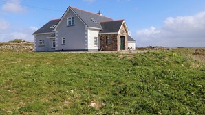 A house with a stone facade, a grey roof, and a grassy field in the foreground. - Tí Tom Nárta (Teeranea)