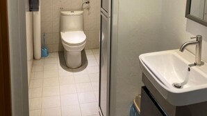 A bathroom with a toilet, sink, and shower area.
