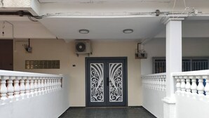 A covered outdoor area with a black and white decorative door, white walls, and a tiled floor.