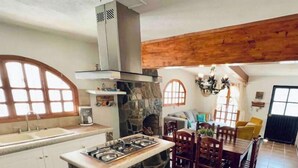 Una cocina con una isla de piedra, estufa integrada y chimenea de piedra.