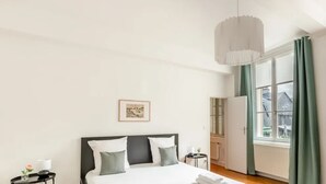 Un dormitorio con cama, mesita de noche, cortinas y vistas al exterior.