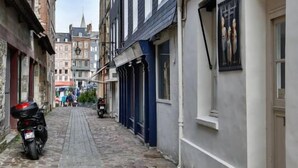 Una estrecha calle adoquinada flanqueada por edificios históricos, algunos mostrando signos de desgaste y otros con fachadas modernas.