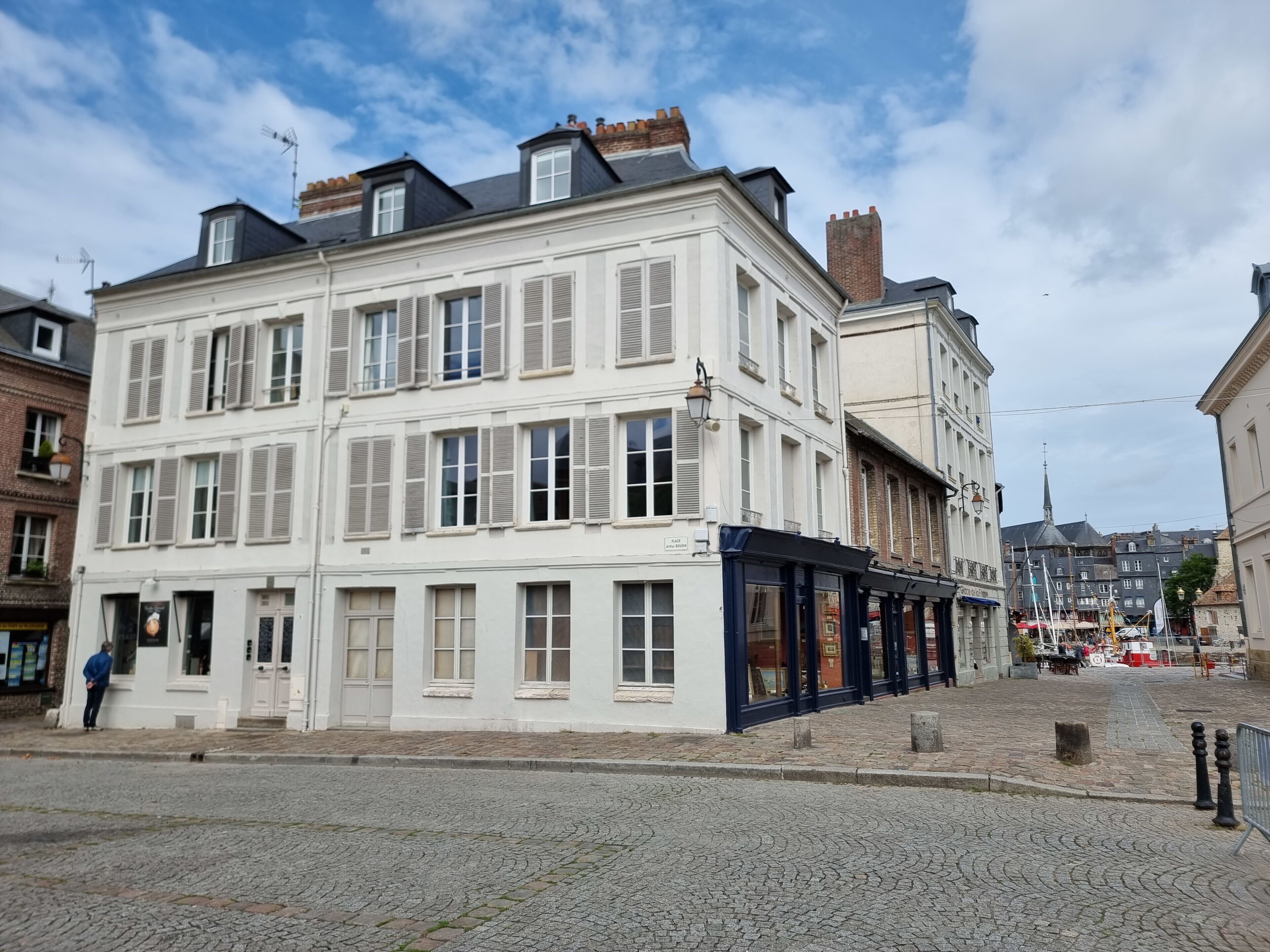 A multi-story building with a white facade and dark blue storefront.