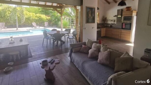 A spacious living area with a pool, a dining set, and a kitchen.