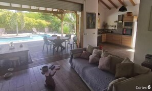 Een ruime woonkamer met zwembad, eethoek en keuken.