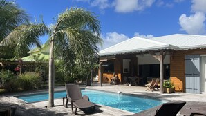 A poolside area with lounge chairs, a wooden deck, and a building with a white roof.