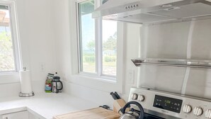 Ett modernt kök med en spis i rostfritt stål, en skärbräda i trä och en vattenkokare.