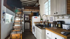 Eine Küche mit einer Holbank, einem Kühlschrank, einer Spüle und einem Schild mit der Aufschrift 'WELCOME TO THE HOUSE EXPERIENCE'.
