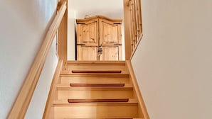 Un escalier en bois, doté d’une rampe, mène à une porte en bois située en haut.