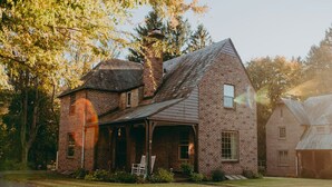 A brick house with a gabled roof, a porch, and a chimney. - The Conestoga Cottage | Hot Tub, Rustic Charm, Near Downtown Lancaster (Conestoga)