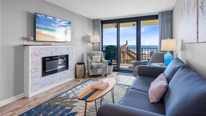 A living room with a fireplace, a sofa, a TV, and a balcony with a view. - Phoenix II 2012 (Orange Beach)