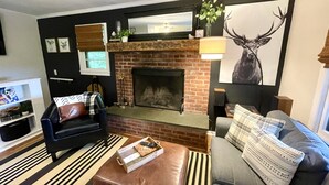 A living room with a fireplace, a sofa, a coffee table, and a television. - Cozy Manchester Getaway with Amazing Views!!! (Winhall)