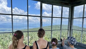A group of people looking out from a large window with a view of a forested landscape. - Cozy Manchester Getaway with Amazing Views!!! (Winhall)