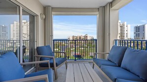 Un balcon avec des meubles bleus, une vue sur des immeubles et un ciel dégagé.