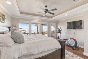 A bedroom with a bed, a ceiling fan, a treadmill, and a TV.