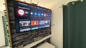 Un téléviseur à écran plat fixé à un mur en pierre, avec une étagère en bois en dessous sur laquelle est inscrit le mot « Détendez-vous ».
