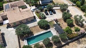 Vue aérienne d’une propriété résidentielle dotée d’une piscine, de panneaux solaires et d’un espace de stationnement.