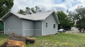 A single-story house with a grey exterior and a metal roof. - Wonderful two-bedroom home with a full kitchen (Pierre)