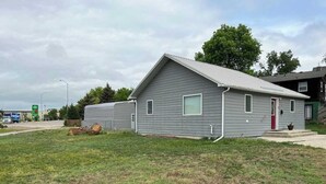 A single-story building with a gabled roof, a front door, and a small porch. - Wonderful two-bedroom home with a full kitchen (Pierre)