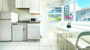 Cocina moderna con armarios blancos, un microondas y un lavamanos. Se ve una ventana con vistas a edificios y plantas.