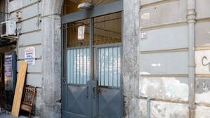 A building with a metal gate, a wooden chair, and a signboard. - Giardino Segreto - Via Foria 216 (Ammezzato) (Napoli)