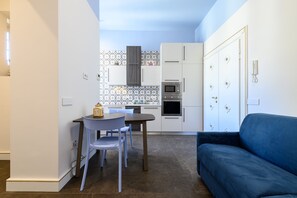 A compact kitchen with white cabinets, a microwave, and a small dining table with chairs.