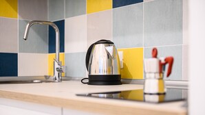 Una cocina con hervidor, grifo y un recipiente pequeño con utensilios.