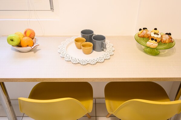 Una mesa con un frutero, un mantel de encaje y un plato de pasteles.