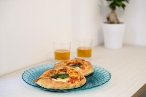 Duas pizzas sobre um prato de vidro azul, com dois copos de cerveja ao fundo.
