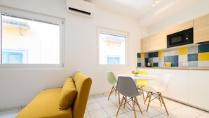 A modern kitchen with a microwave, a dining area with chairs, and a sofa. - Via S. Liborio 79 - 5° Piano (Napoli)