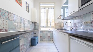 Cuina estreta amb rajoles decorades, una finestra amb cortines i un rentamops.