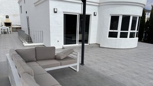 A modern outdoor living area with a sectional sofa, a pergola, and a patio table. - VILLA NEILA, with heated pool  (URBANIZACIÓN PUERTO AZUL, TARAJALEJO)