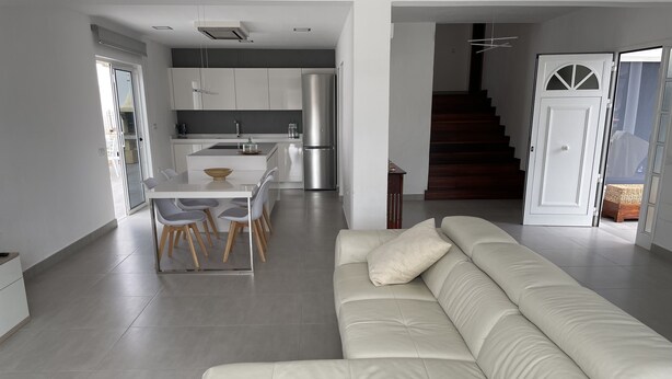 A modern living room with a white leather sofa and a dining area with a white table and chairs. - VILLA NEILA, with heated pool  (URBANIZACIÓN PUERTO AZUL, TARAJALEJO)