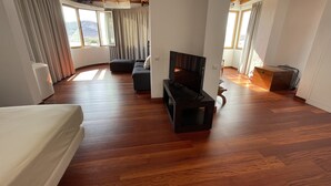 A spacious room with wooden flooring, a sofa, a TV, and a view of the outdoors through large windows. - VILLA NEILA, with heated pool  (URBANIZACIÓN PUERTO AZUL, TARAJALEJO)
