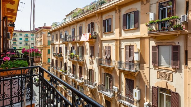 Une rangée d’immeubles à plusieurs étages, dotés de balcons, dont certains sont ornés de plantes en pot.