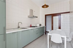 A modern kitchen with a gas stove, sink, and a dining area with a table and chairs.