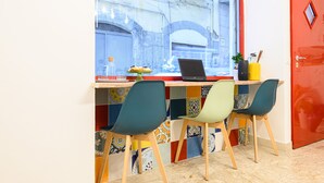 A workspace with a laptop, colorful chairs, and a window with a view of a building. - Via S. Liborio 79 - 6° Piano (Napoli)