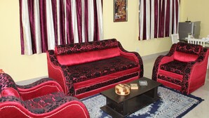 Ein Wohnzimmer mit einer Couch, Sesseln, einem Couchtisch und einem Fernseher.