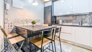 A modern kitchen with a dining table, chairs, and a microwave.