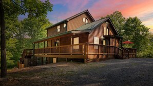 Eine zweistöckige Blockhütte mit überdachter Veranda und einem umzäunten Deck.